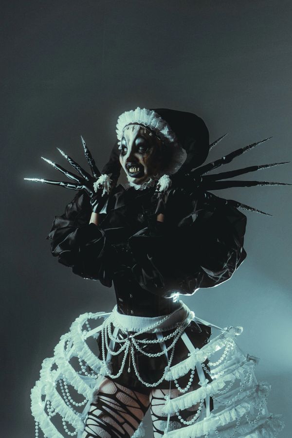 Person in eerie gothic costume with clawed gloves and skeletal makeup.