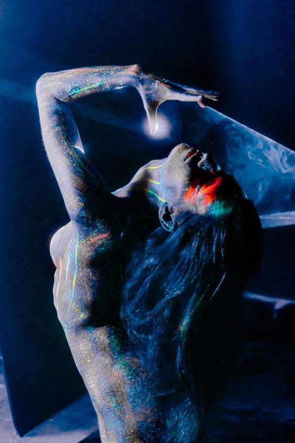 Artistic body painting with glowing neon colors under blacklight.