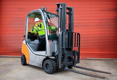A man driving a forklift and giving a thumbs up