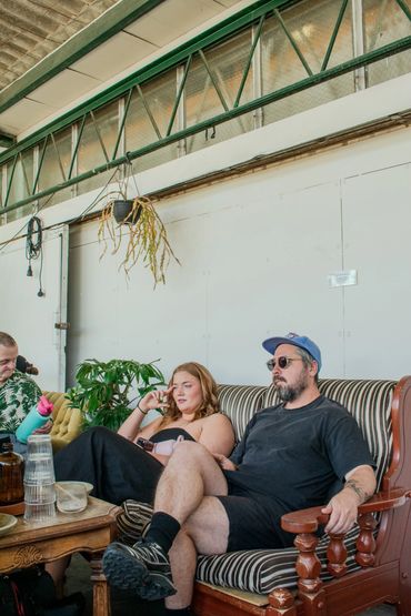 Three people sitting on vintage sofas in a relaxed indoor setting.