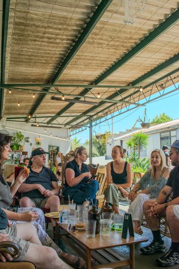 Group of people socializing at a cozy outdoor café under a covered patio.