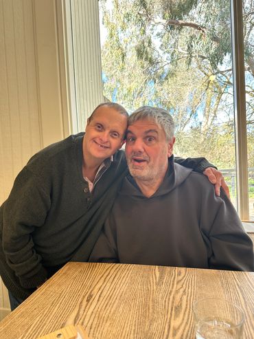 Two clients seated together at a table, showing supportive disability and NDIS support services in A