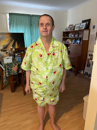 Man wearing bright green Grinch-themed pajamas standing indoors.