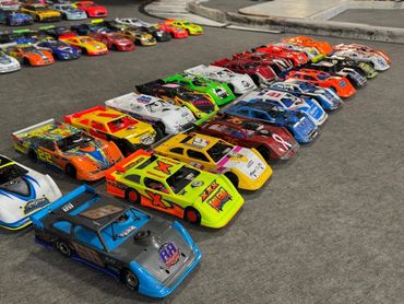 Rows of colorful toy race cars lined up on a gray surface.