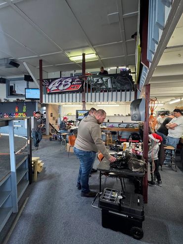 A lively indoor RC car racing facility with people working and socializing.