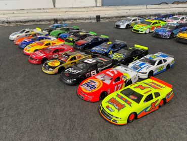 A lineup of colorful toy race cars arranged on a gray surface.