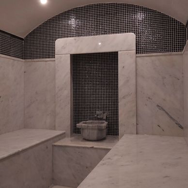 Elegant marble steam room with black tile accents and basin.