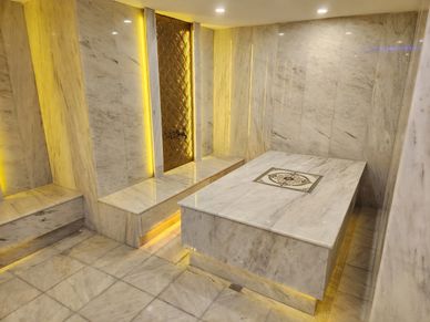 Luxurious marble room with ambient yellow lighting and a central marble slab.