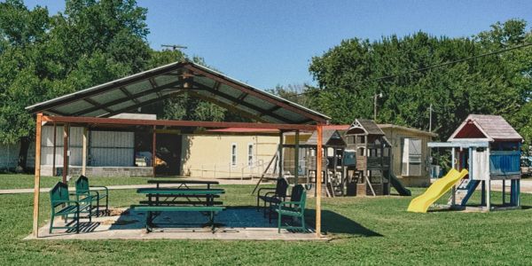 Playground with picnic shelter and play structures on a sunny day.