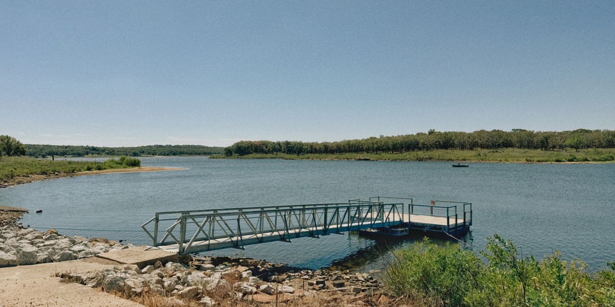 Empty dock on a calm lake under clear sky.
