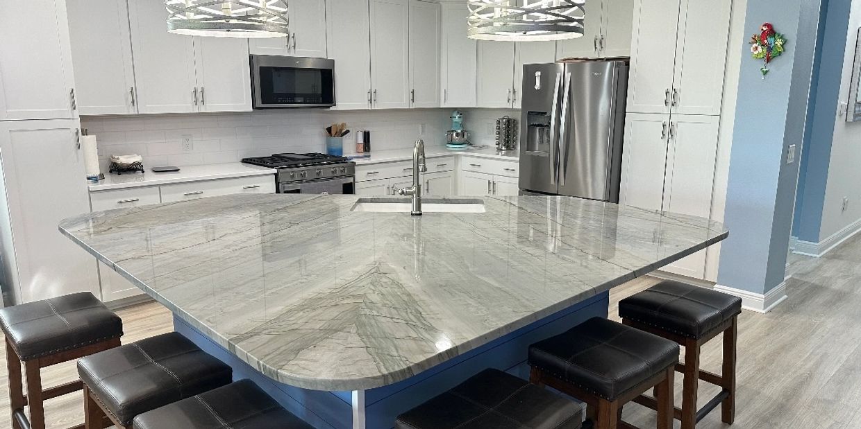 Modern kitchen with a large marble island and six cushioned stools.