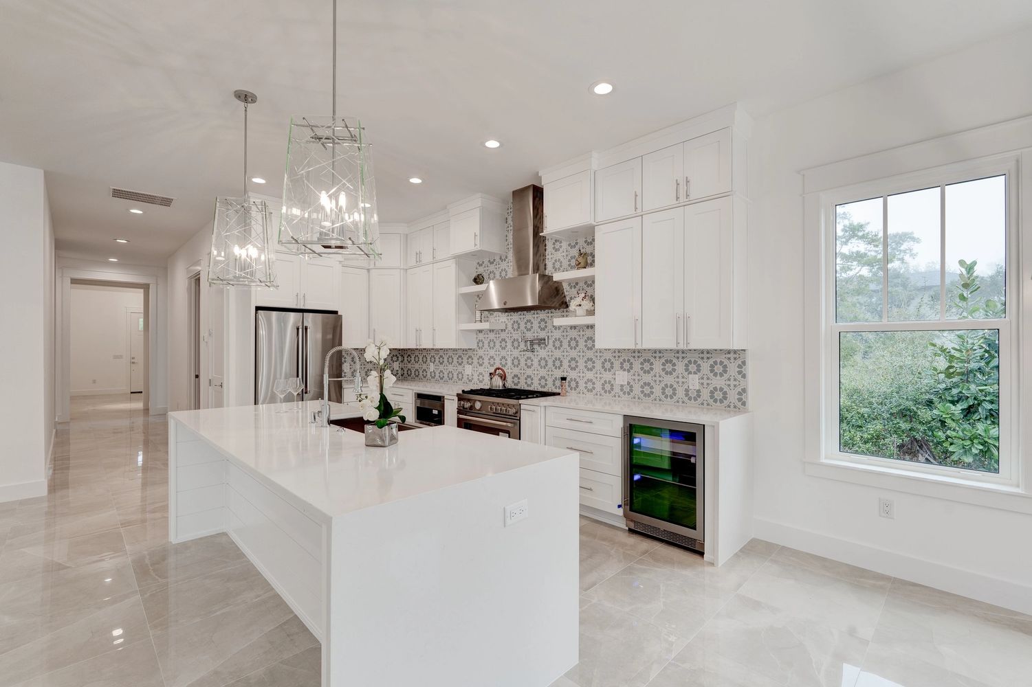 Bright modern kitchen with white cabinetry and patterned backsplash.