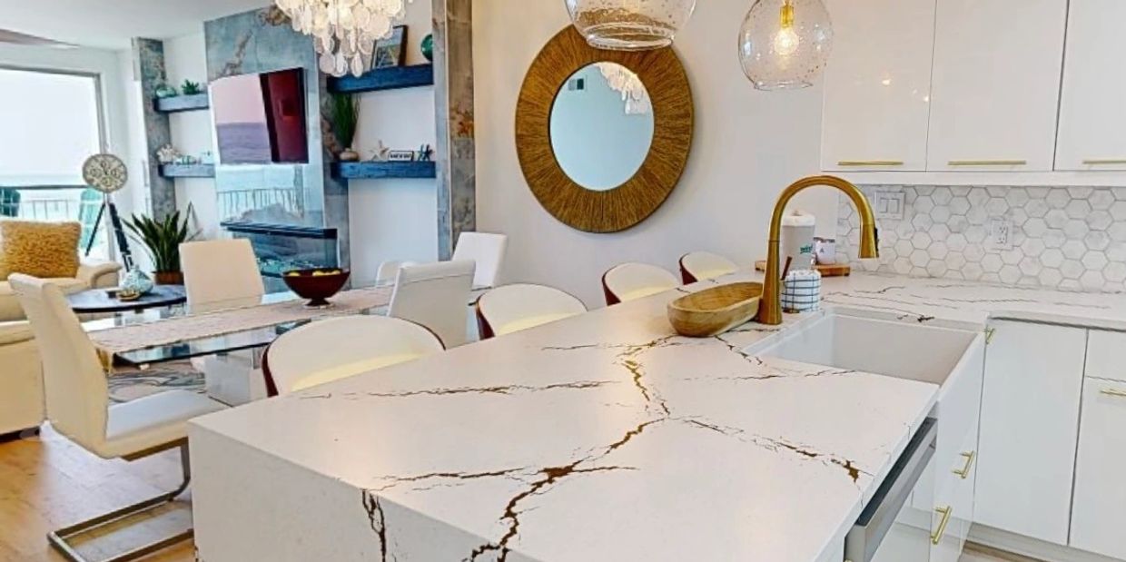 Modern kitchen and dining area with marble island and elegant lighting.