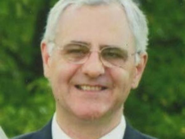 Smiling older man with glasses outdoors.