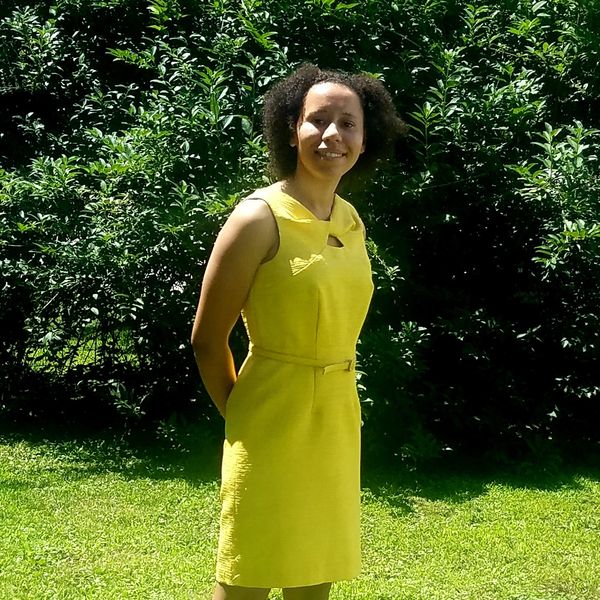 Woman in a yellow dress smiling outdoors.