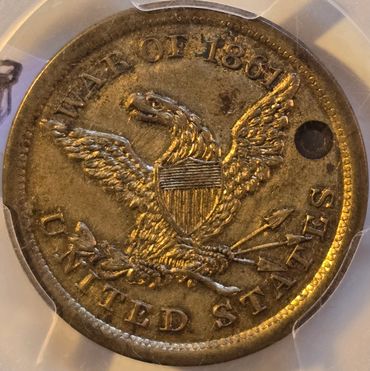 Old 1861 United States coin with eagle design and hole.