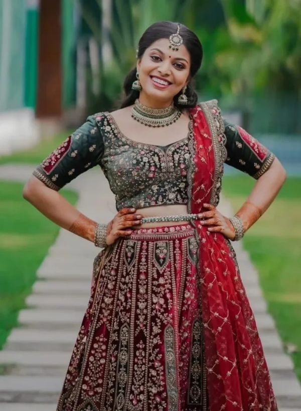 Smiling woman in intricate traditional Indian attire with jewelry and henna.