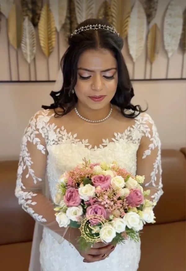 Bride in a white lace gown holding a bouquet of pink and white roses.