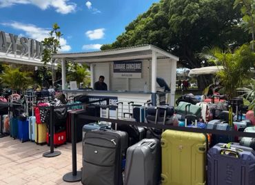 Luggage concierge booth surrounded by numerous suitcases in an outdoor area.