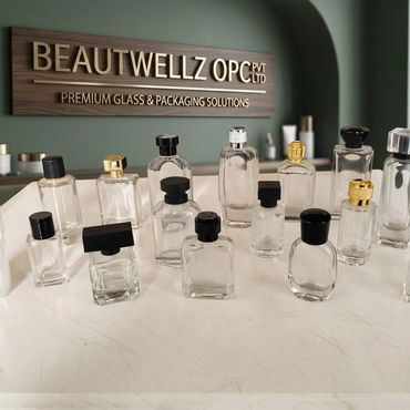 Various empty glass perfume bottles displayed on a white surface under a premium packaging sign.