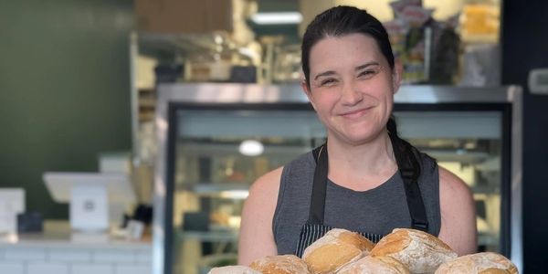 Smiling baker holding fresh bread in bakery.