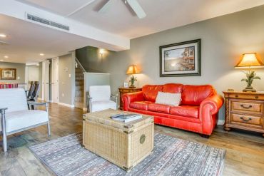 Bright living room with red sofa and wicker coffee table.