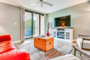 Bright living room with red couch and wooden chest coffee table.