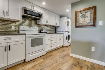 Modern kitchen with white cabinets and stacked washer and dryer.