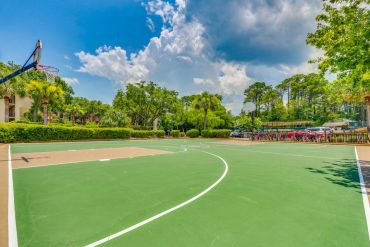 Resort outdoor basketball court under a blue sky with clouds.