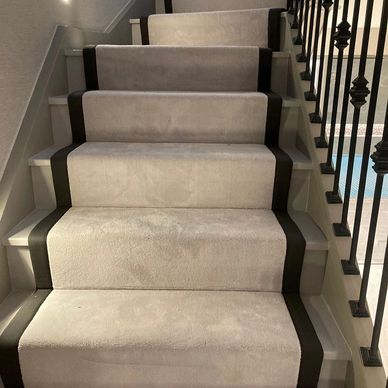 Front shot of luxury house staircase that is decorated with beige color carpet stair runner
