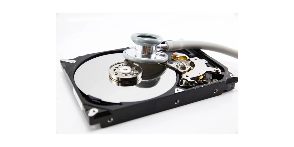Stethoscope laying on top of hard drive. Hard drive cover taken off, internal components visible. 