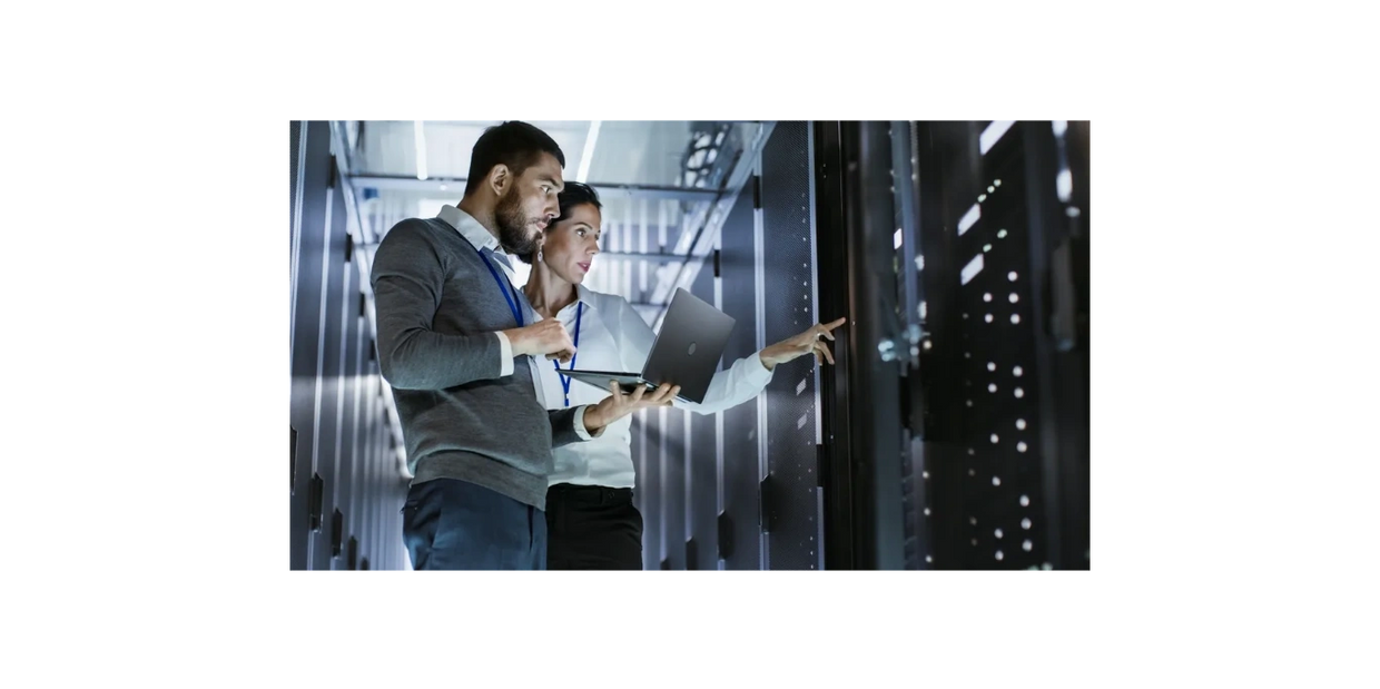 Man and woman in IT server room. Man is holding a laptop.