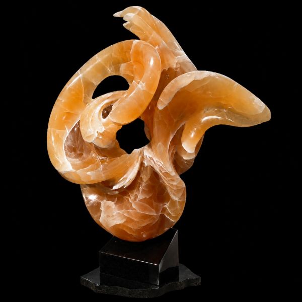 Abstract orange stone sculpture on a black base.
