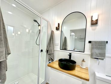 Bathroom renovation featuring a shower, vanity, mirror, wall sconces, toilet and vj board