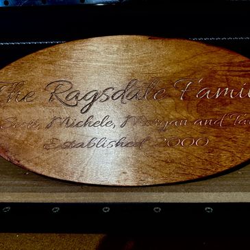 Wooden oval plaque with engraved family name and details.