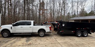 White pickup truck towing a black trailer in a driveway.