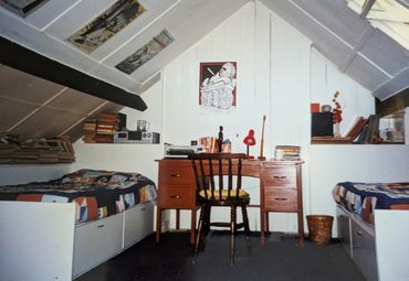 Cozy attic bedroom with twin beds and a wooden desk.