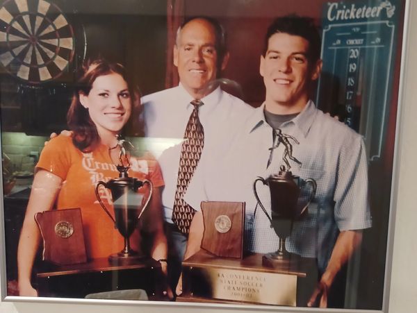 Three people posing with trophies and plaques.