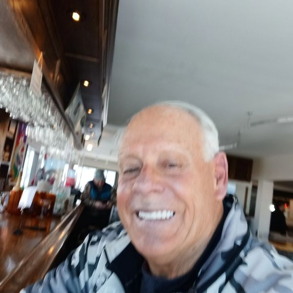 Smiling elderly man in casual wear inside a bar.