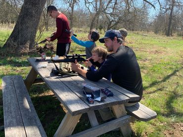 A father teaching his young son how to properly and safely fire a .22 rifle.