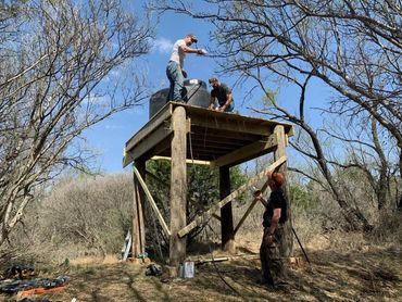 Guys constructing a water tower on a hill.