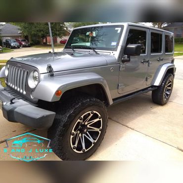Shiny silver Jeep Wrangler parked on a driveway after detailing.