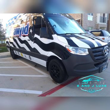 Black and white striped Mercedes van with social media logos parked outside.