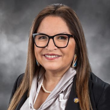 Professional woman wearing glasses and a pearl necklace.
