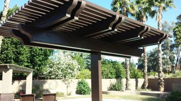 Brown wooden pergola in a sunny backyard with greenery.
