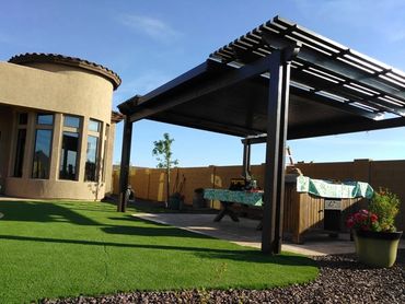 Modern backyard with artificial grass and covered patio seating area.