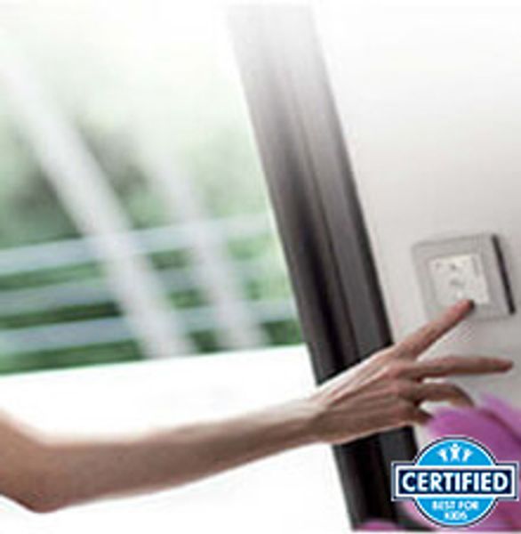 Hand pressing a light switch near a window with a certified badge.