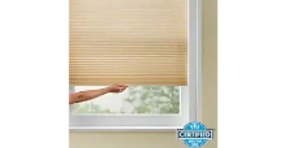 Hand adjusting a beige window blind with a certification badge.