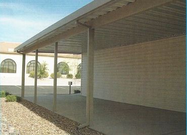 Covered outdoor patio area with concrete floor and gravel landscaping.