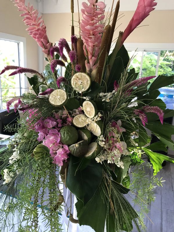 Tischschmuck - schlankes hohes Mittelstück. Pink und grün mit Limonen. Im Hintergrund Fenster
